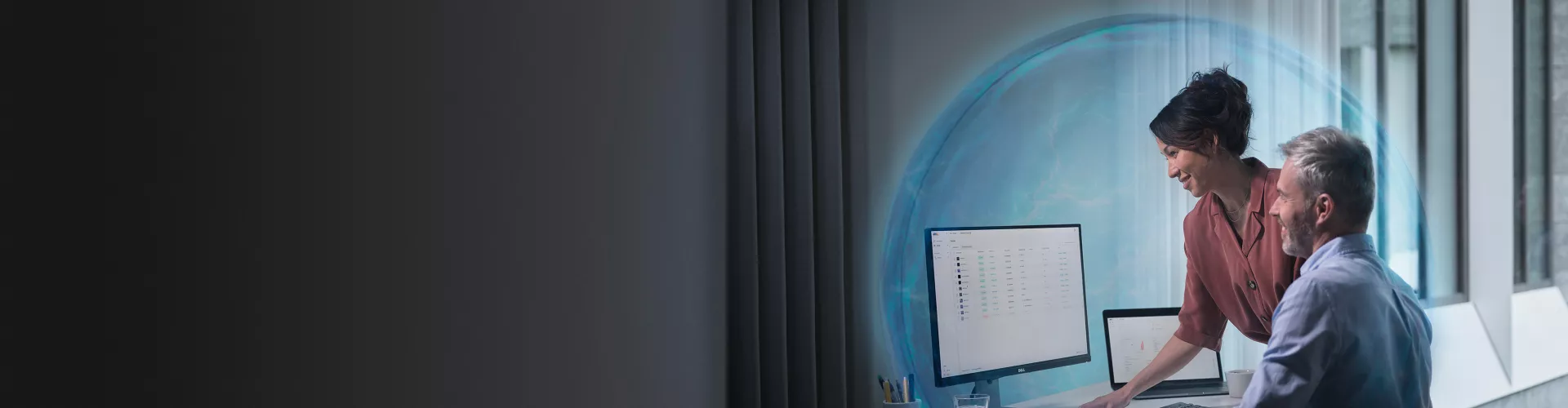 Two people in front of a computer screen, one of them pointing at it.