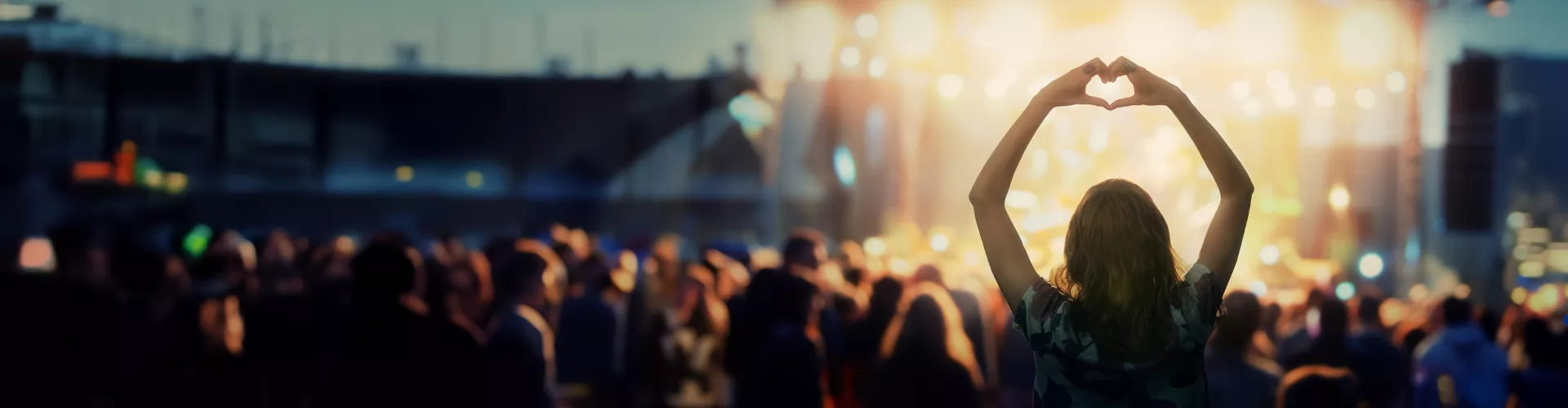 Concert with people and a woman holding hands shaped like a heart.