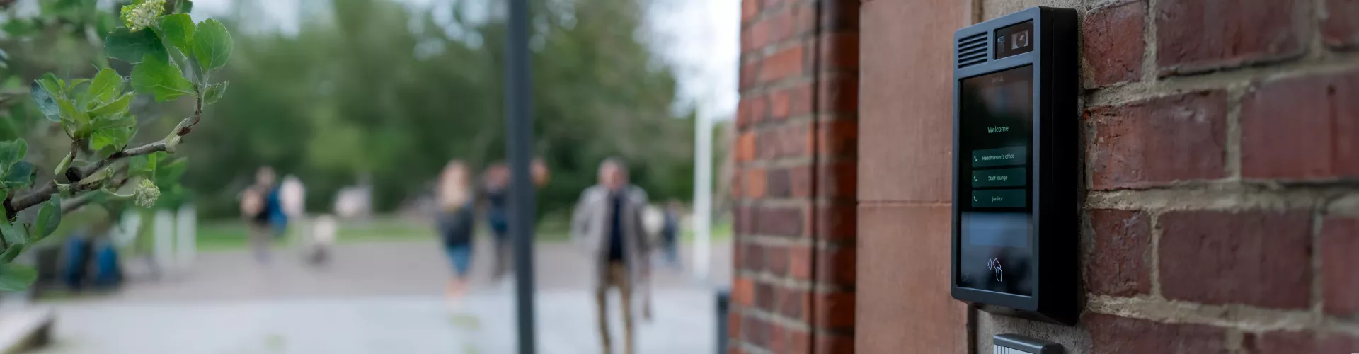 AXIS I8307-VE Network Video Intercom, mounted on a brick wall in an outdoor environment