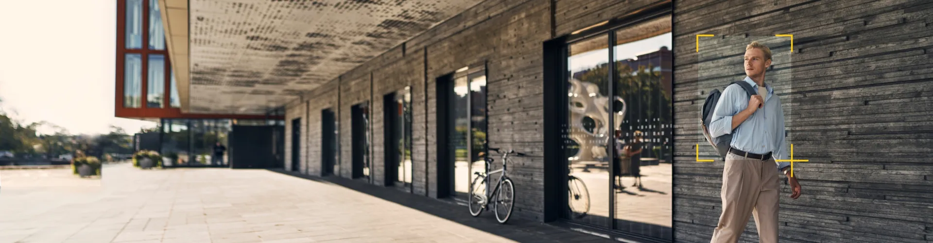 Man walking outside a big building with object detection frame around him.