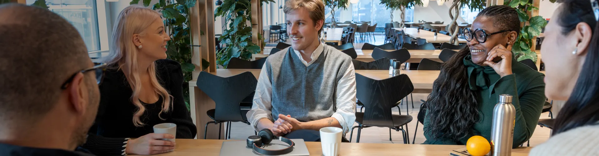 A group of Axis colleagues socializing and enjoying a break in the bright canteen at the Lund headquarters.