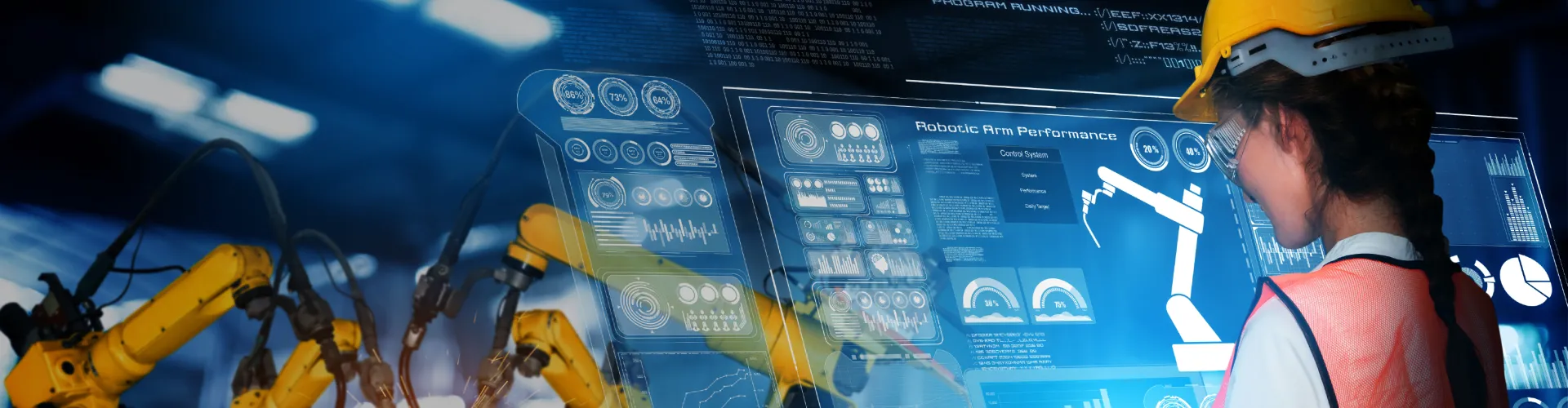Woman wearing a hardhat and working on a overlay screen to control robot arms.