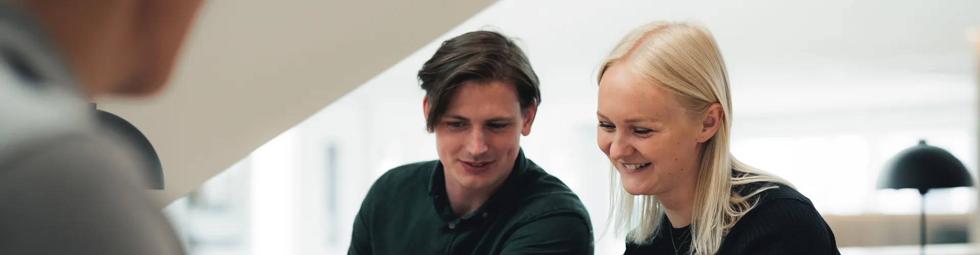 Two people sitting together and smiling at a laptop.