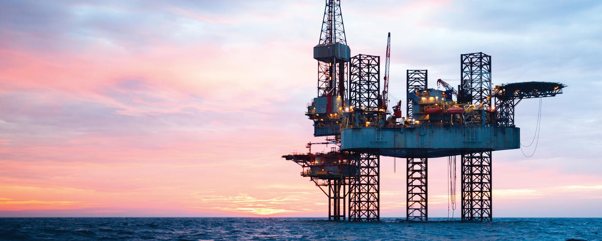 Oil rig in ocean during sunset