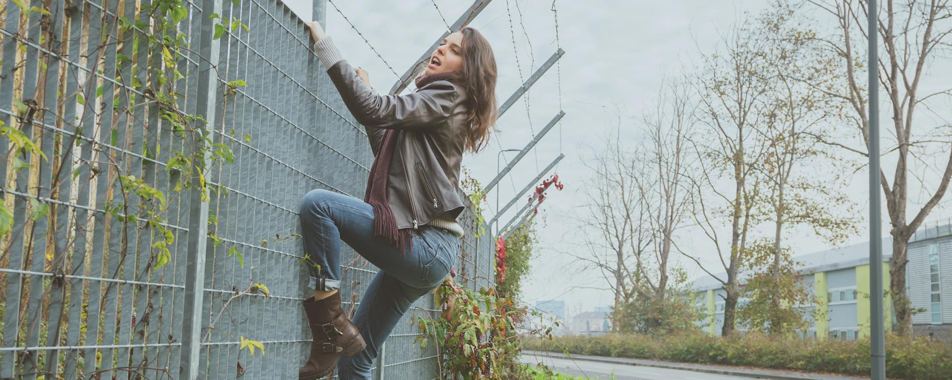 woman climbing on a fence