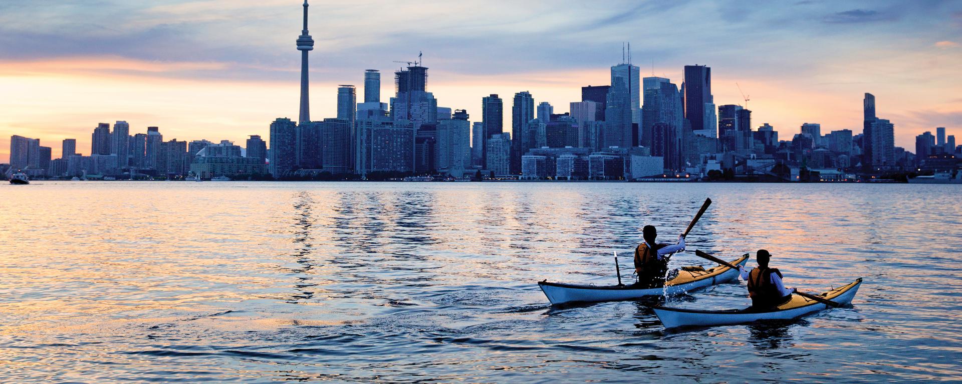 Two people are paddling in kayaks in the city skyline
