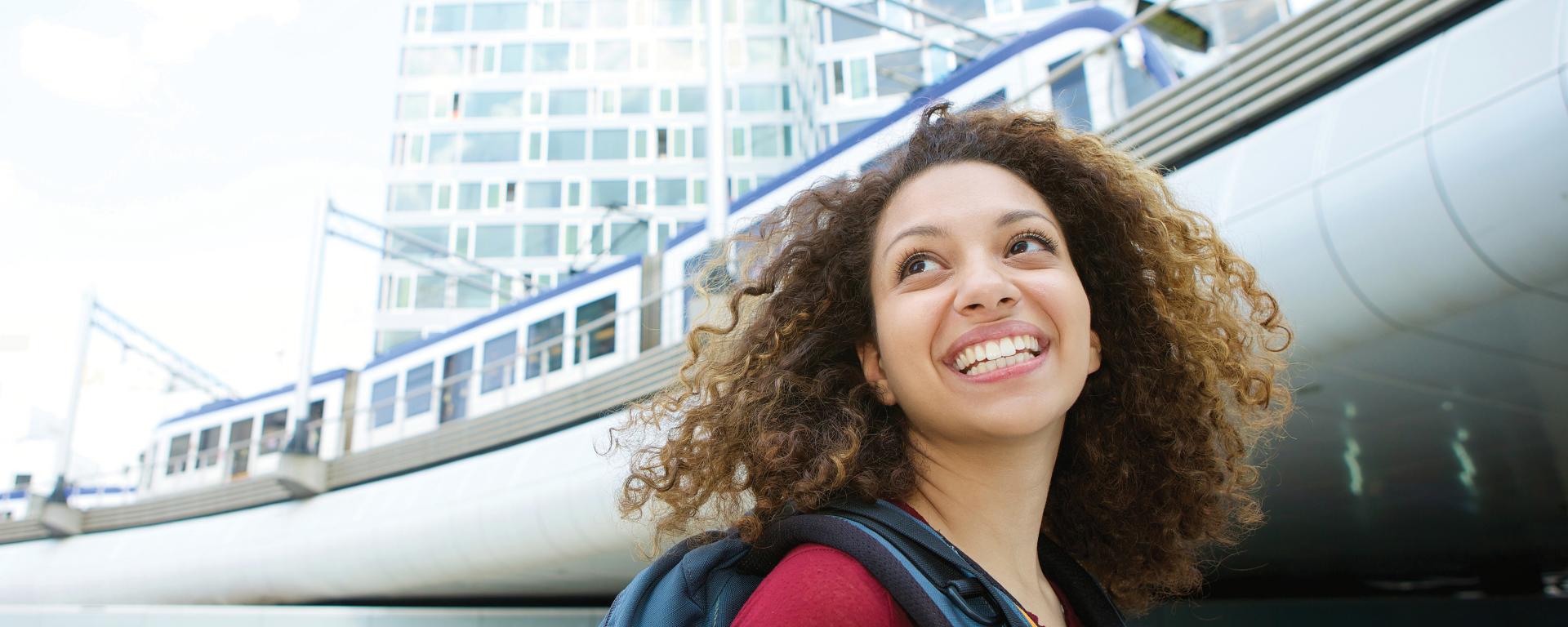 woman backpack smiling outside train station