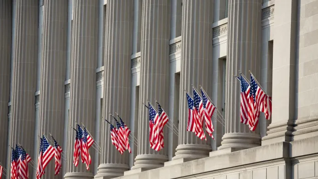 Close-up of a government building with several US flags hanging from the wall.