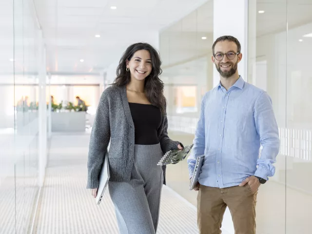 A woman and a man standing beside each other and smiling at the camera in the office.