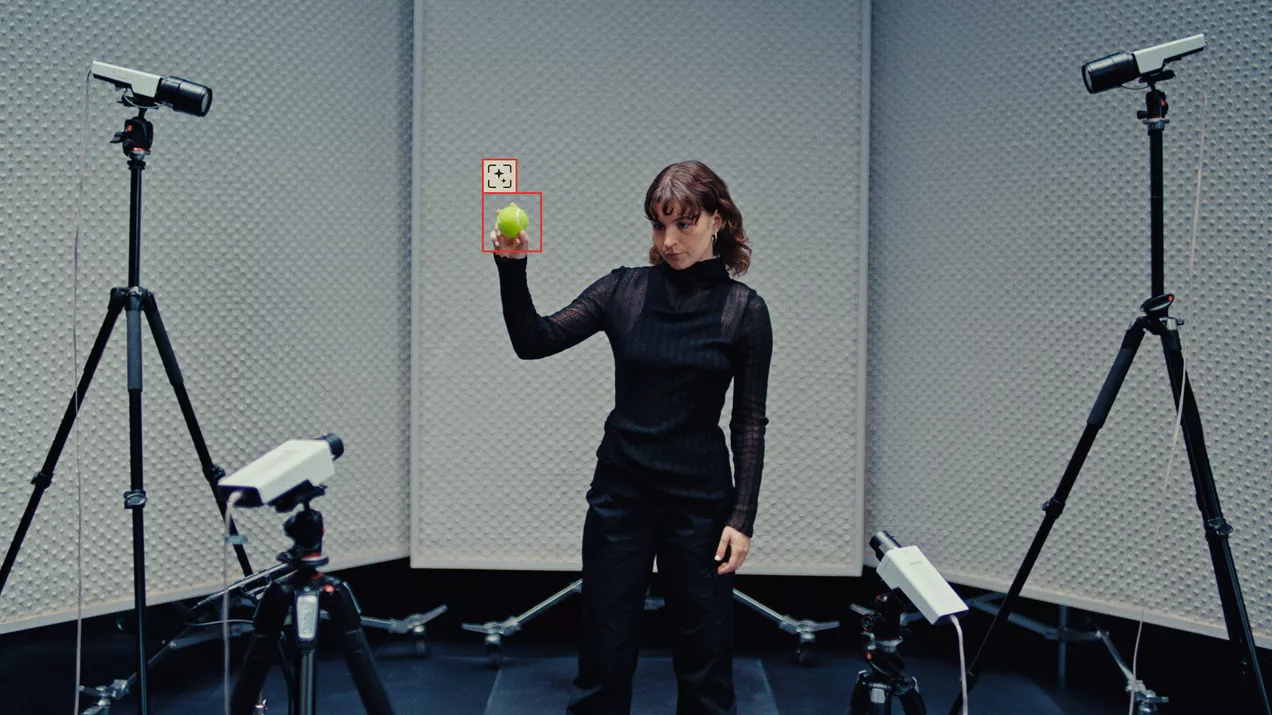 Woman standing in the middle and holding an object in front of four Axis cameras with object detection surrounding her. 