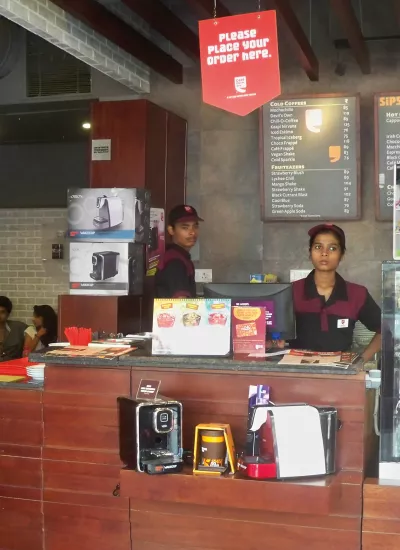 Coffe place front desk, two employees behind.