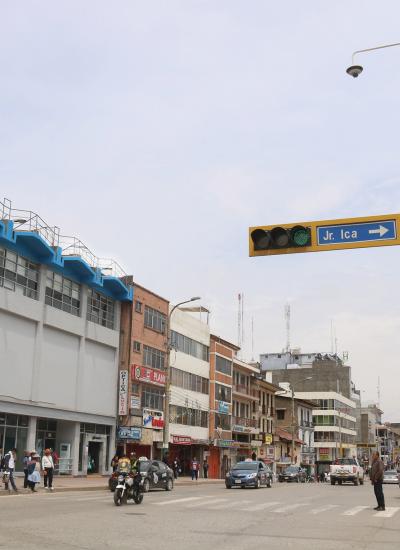 City street in Peru with cars, people and yellow pole for traffic light.