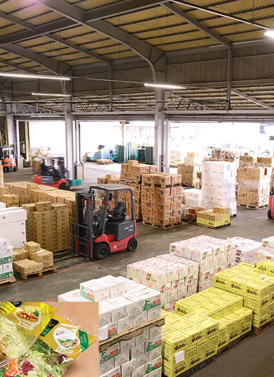 Warehouse with trucks and magnification of vegetables in left corner.