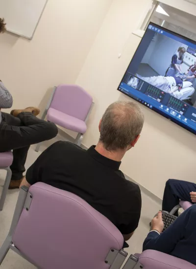 Three men and an instructor viewing a monitor screen of clinical training.