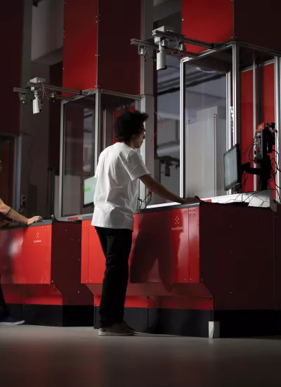 Two men at red warehouse station looking through a glass window.