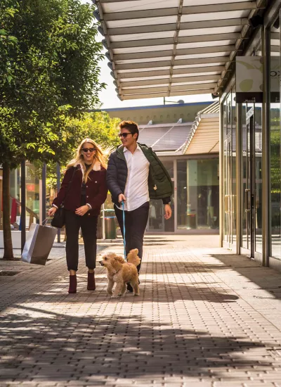 Man and woman walking dog outside shopping mall