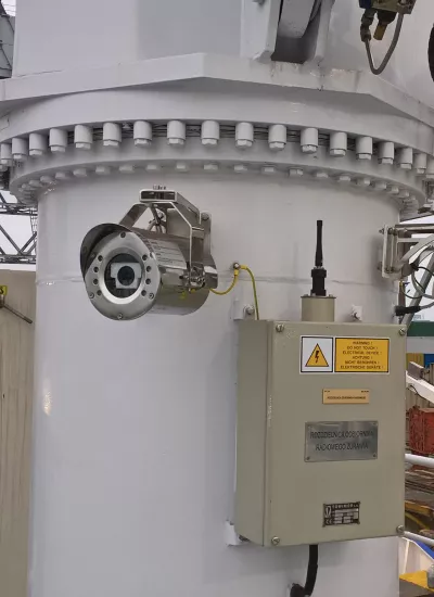 Cameras mounted on white pole on ship overlooking harbour. 