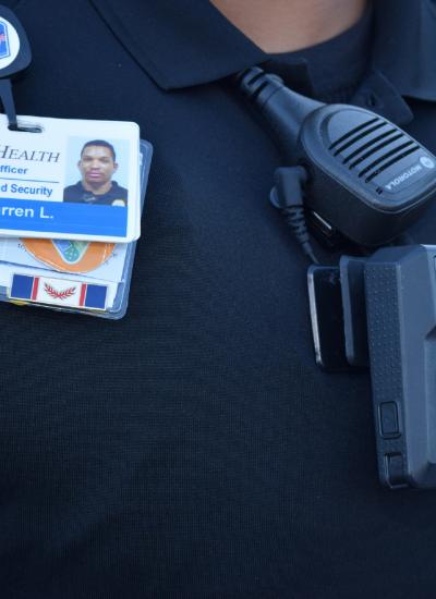 Close up of security officer's chest showing body worn camera, ID, and badge