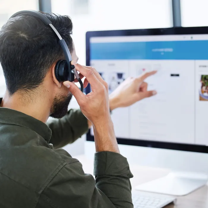 Man talking on the phone while point at the computer screen