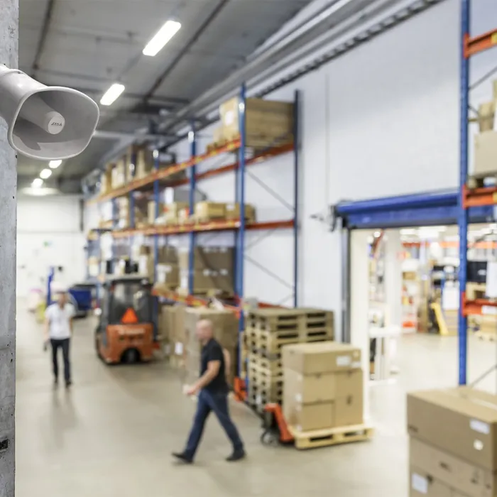 A speaker hanged on the wall inside a warehouse.