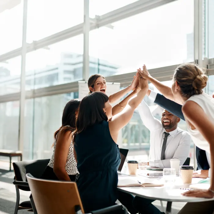 Work colleagues high fiving in a meeting.