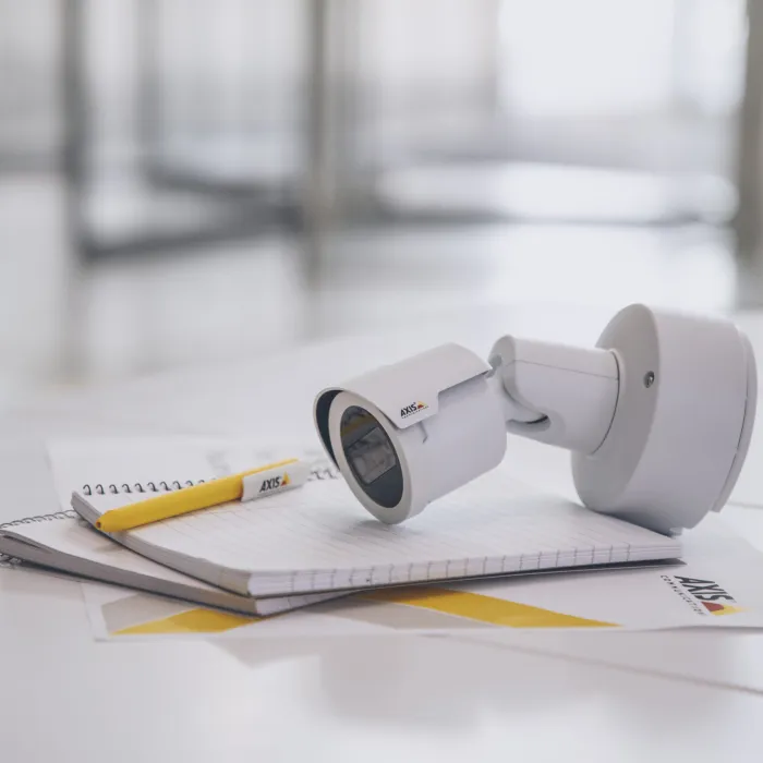 A camera with a pen and paper on top of a desk.