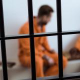 Prisoners in orange jumpsuit playing a game behind bars