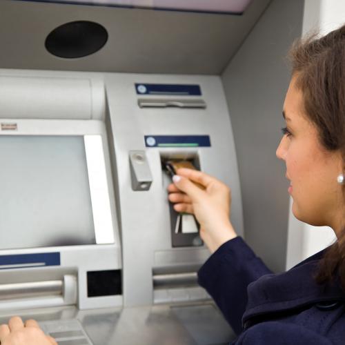 Женщина рядом с банкоматом, вид слева