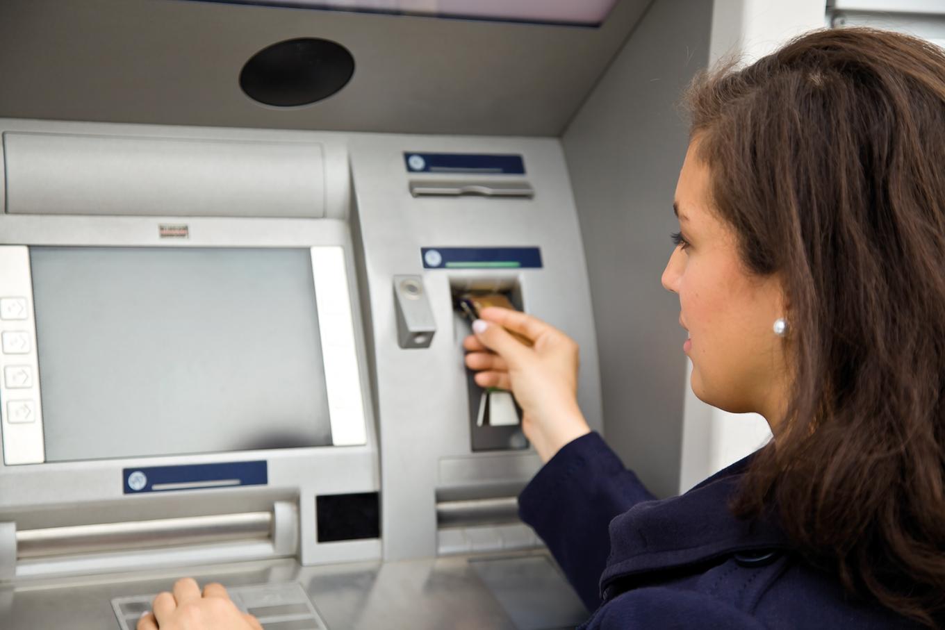 Женщина рядом с банкоматом, вид слева