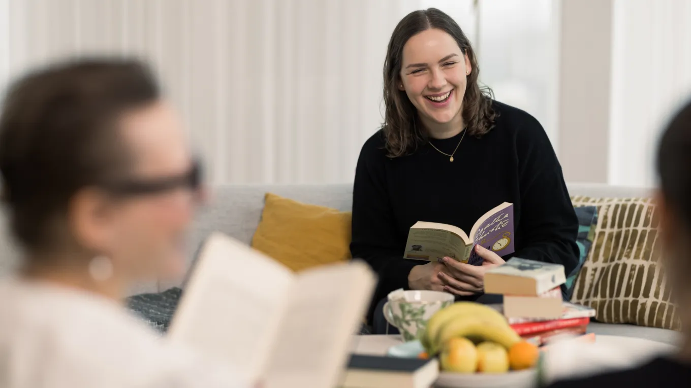 Victoria Vucic seen laughing and holding a book, while sitting in the Axis book club