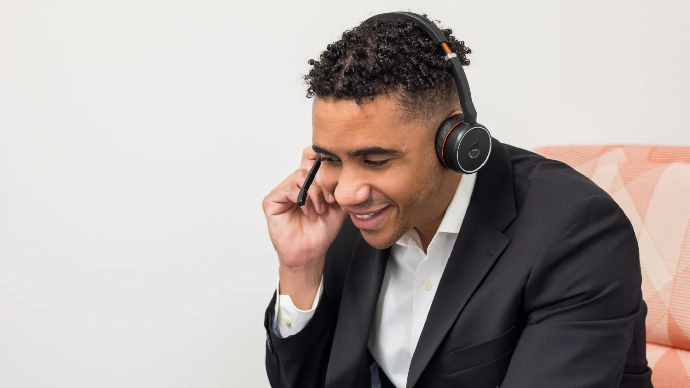 Axis employee Jon-Pablo wearing a headset and smiling while taking a business call.