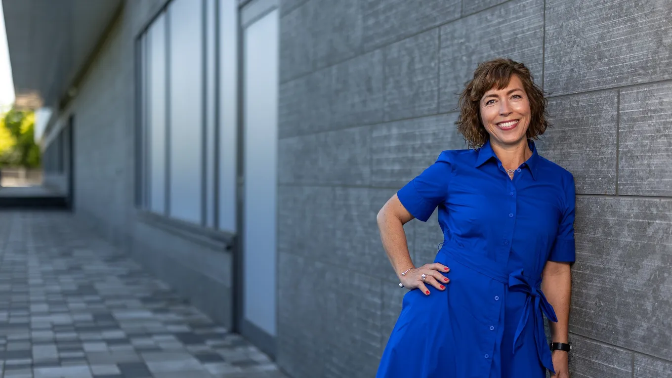 Frida, Manager Business Navigation HQ at Axis, standing in front of the Grenden building, smiling.