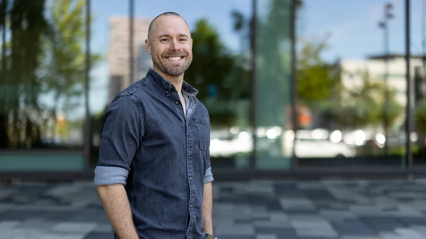 Jonathan, Health and Safety Specialist at Axis, smiling in front of the Grenden building at Axis HQ.
