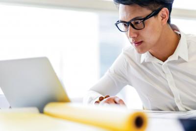 Man with glasses in front of laptop