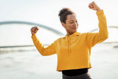 Woman in a yellow sweatshirt, flexing her muscles