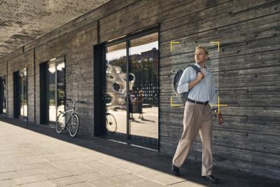 Man walking outside a big building with object detection frame around him.