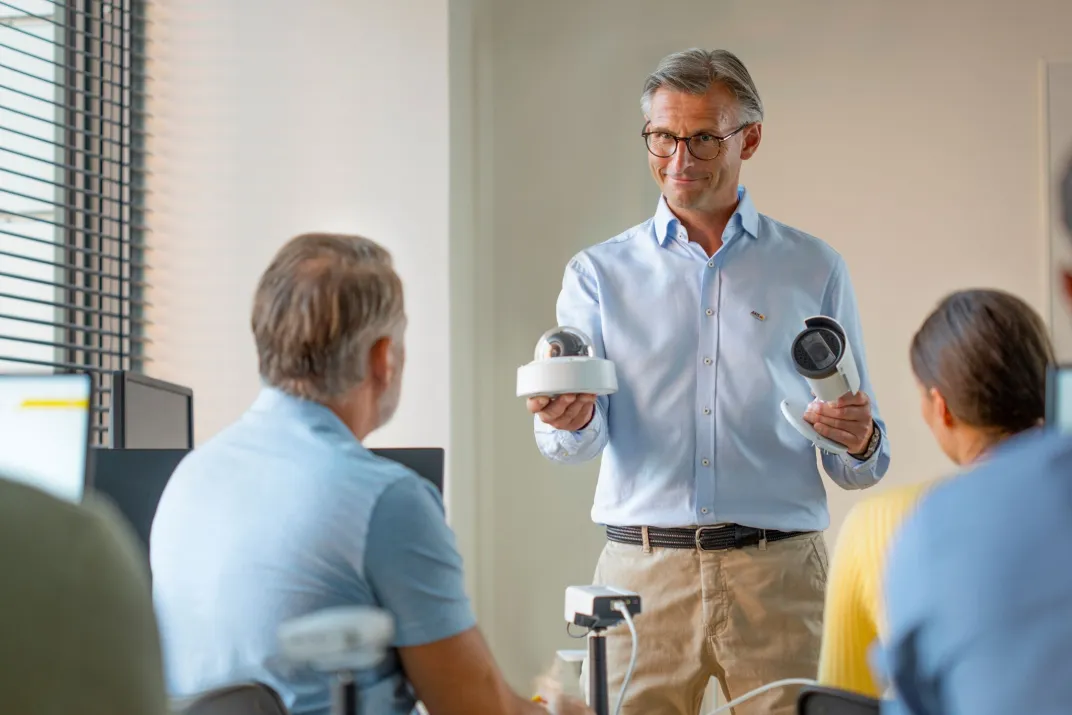 A man teaching about Axis cameras for a room of people in a classroom setting.